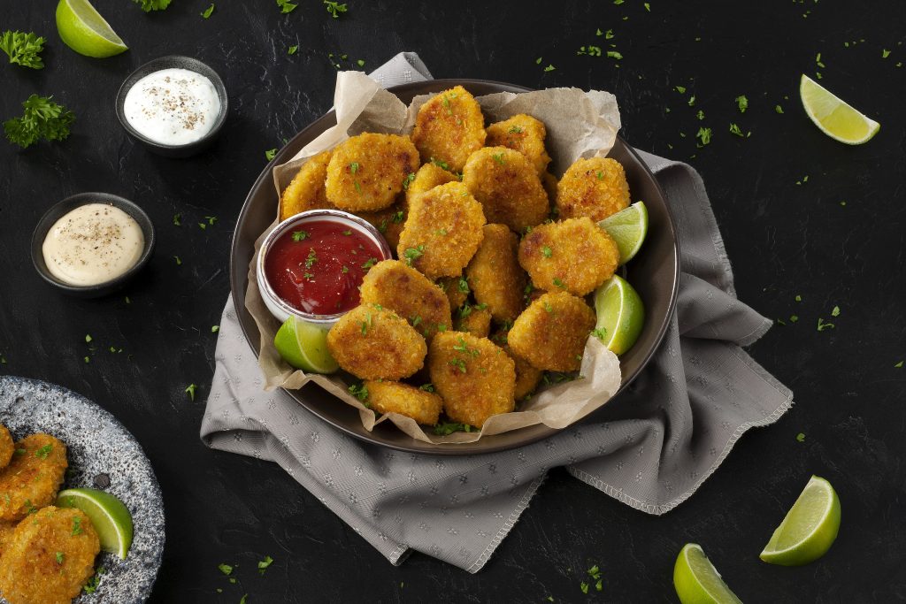 Voorgegaarde en gepaneerde veganistische nuggets op basis van plantaardige eiwitten met toegevoegd ijzer en vitamine B12. Diepvries.