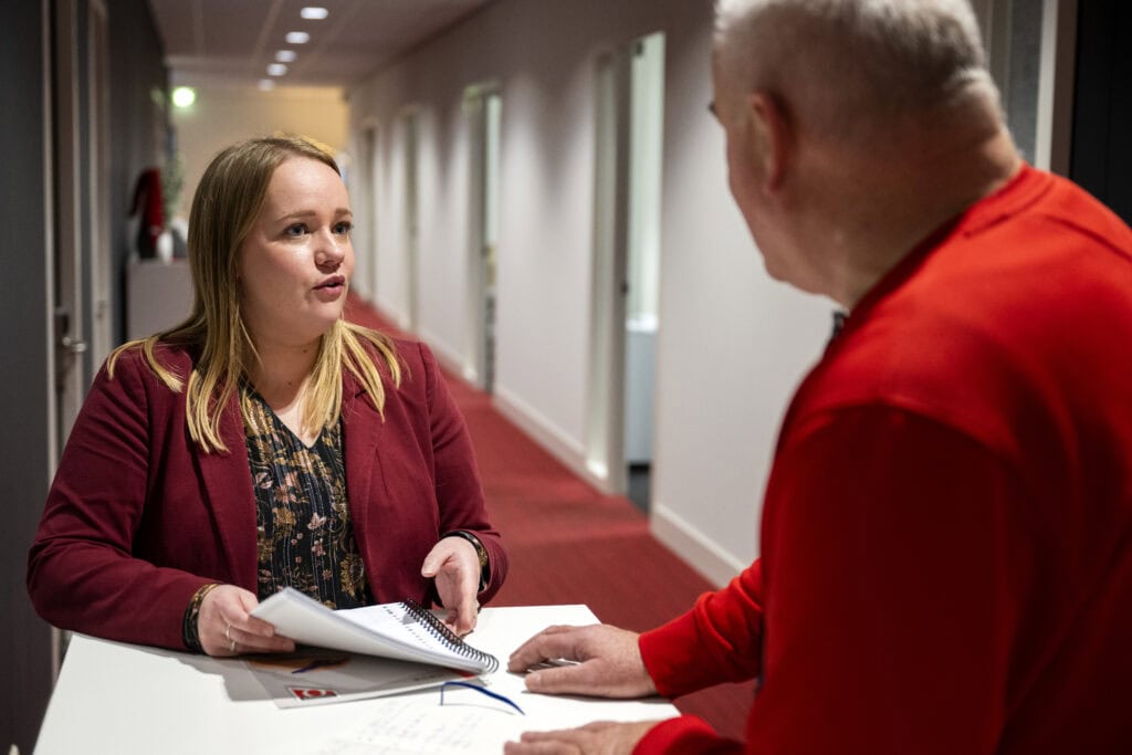 Collega’s in gesprek op de gang met documenten in de hand,