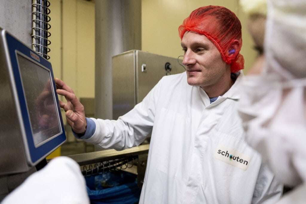 Operator bij Schouten bedient een touchscreenmachine in een hygiënische productieomgeving voor plantaardige producten, met focus en precisie.